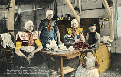 8959 Groepsportret van enkele naaisters en kinderen in klederdracht in hun atelier met meubilair te Spakenburg ...